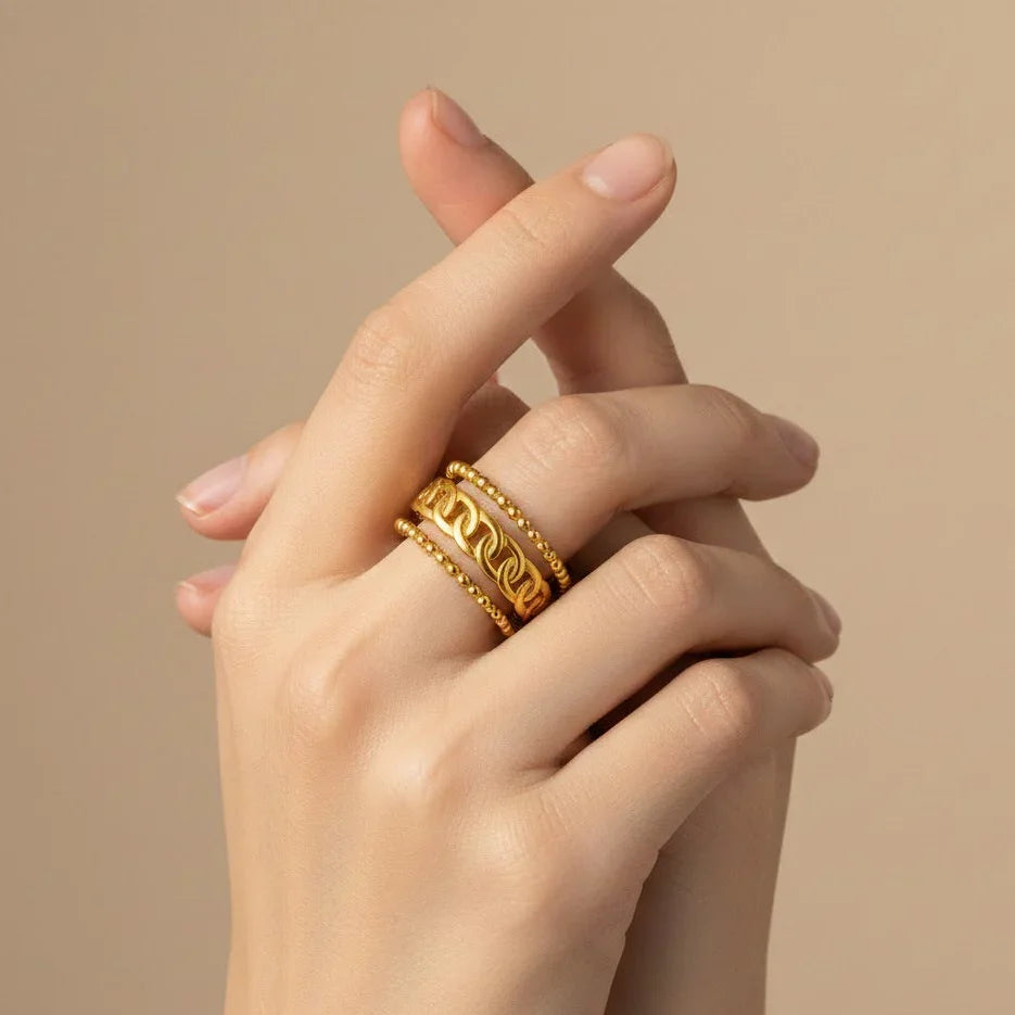 Hand wearing a gold ring on a beige background
